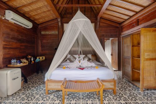 Canopy bed on patterned tiles in the one-bedroom villa
