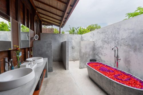 Semi-outdoor bathroom with a flower-filled stone bath