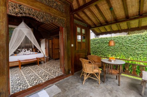 Carved teak doorway of the one-bedroom villa opening to a canopy bed
