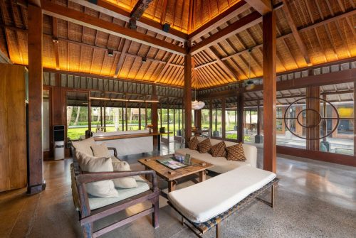 Open Joglo living pavilion with teak beams and white sofas