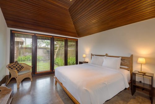 Main villa bedroom with vaulted timber ceiling and garden windows